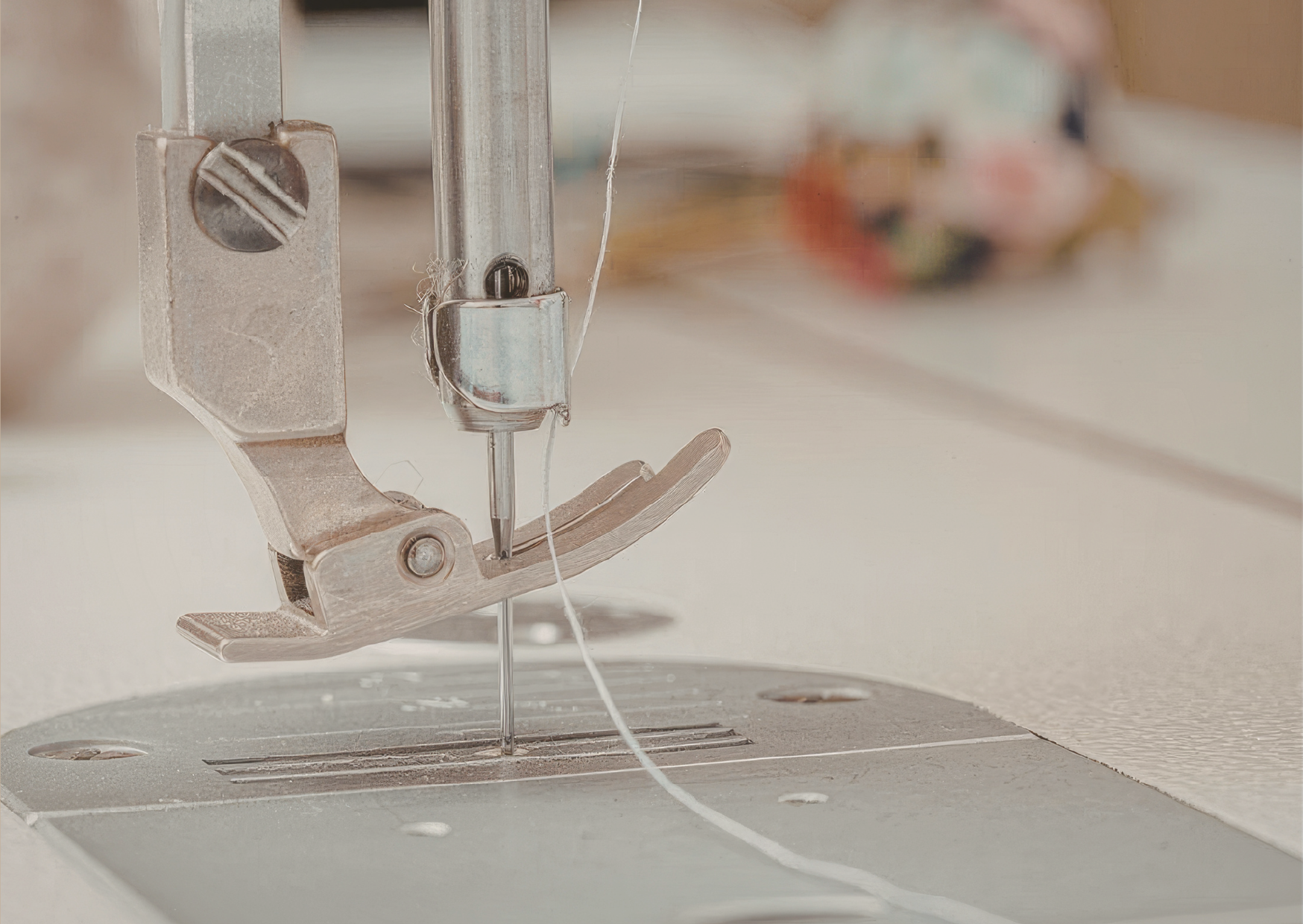 Close-up of a threaded sewing machine needle, presser foot, and needle plate during a professional repair and servicing session.