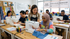 Professional sewing instructor teaching a student how to thread and set up a sewing machine in a creative craft studio.