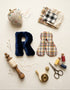Flat lay of a DIY alphabet cushion sewing kit featuring handmade plush letter &