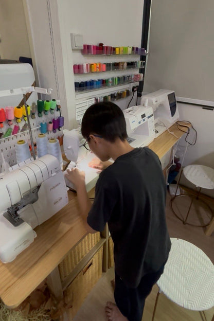 Child sewing their first straight seam on fabric at Envy Her Singapore&