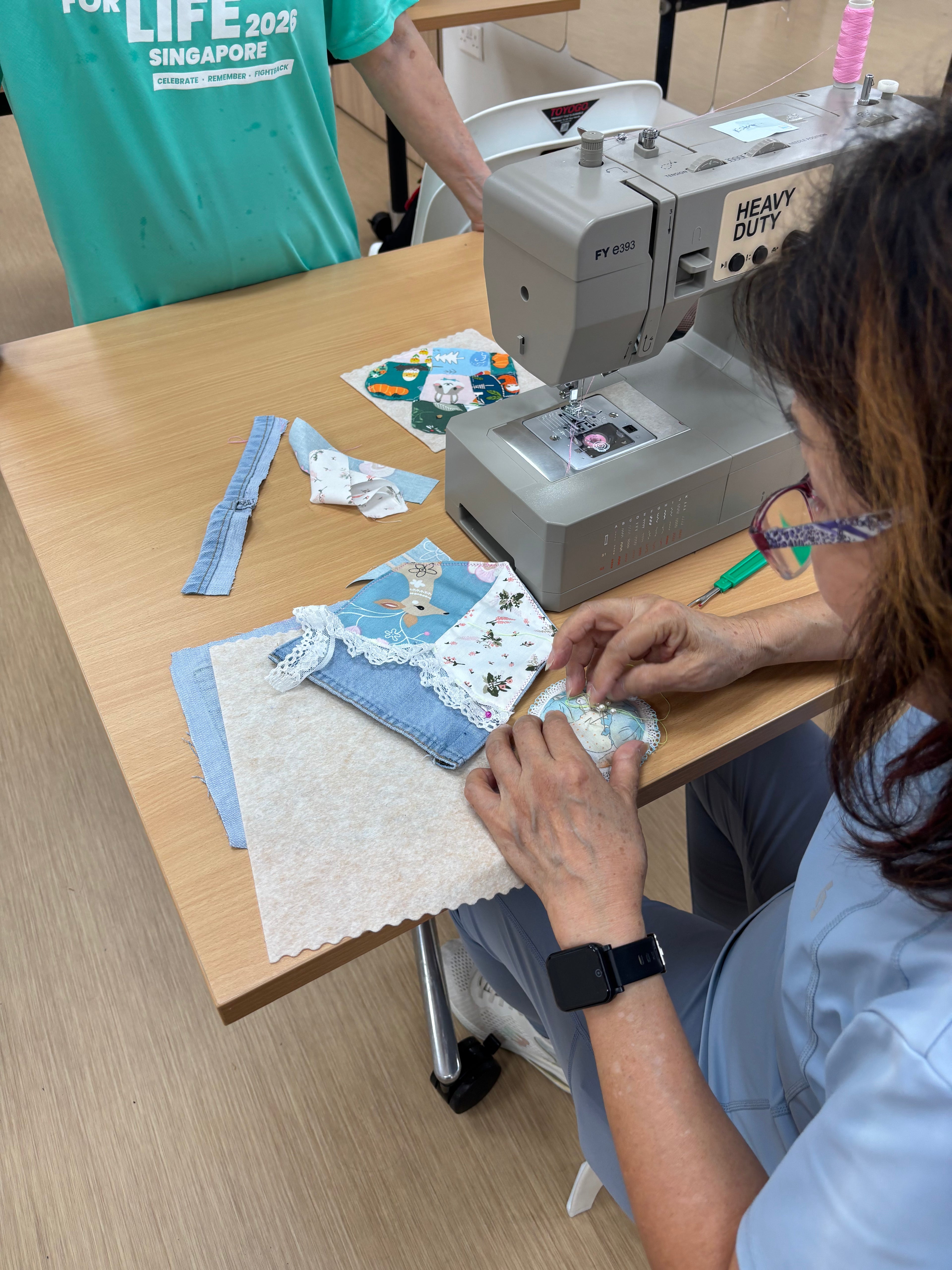 A completed patchwork fabric coaster with a small denim handle, showcasing upcycling techniques learned during a 2-hour beginner sewing workshop