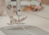 Close-up of a threaded sewing machine needle, presser foot, and needle plate during a professional repair and servicing session.